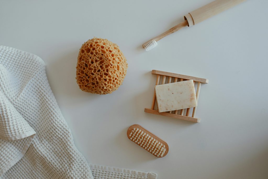Top view of minimalist bathroom essentials including soap, sponge, and tools on a white background.